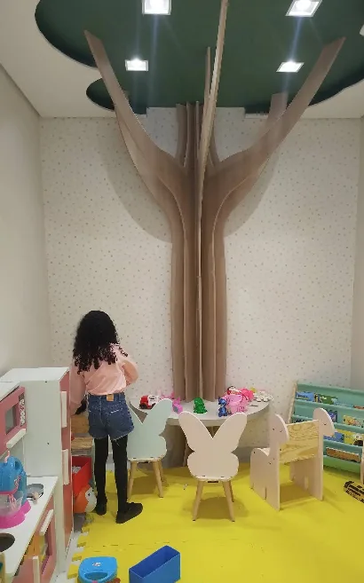 Sala de espera infantil da AmePed, com decoração em formato de árvore e mobiliário lúdico